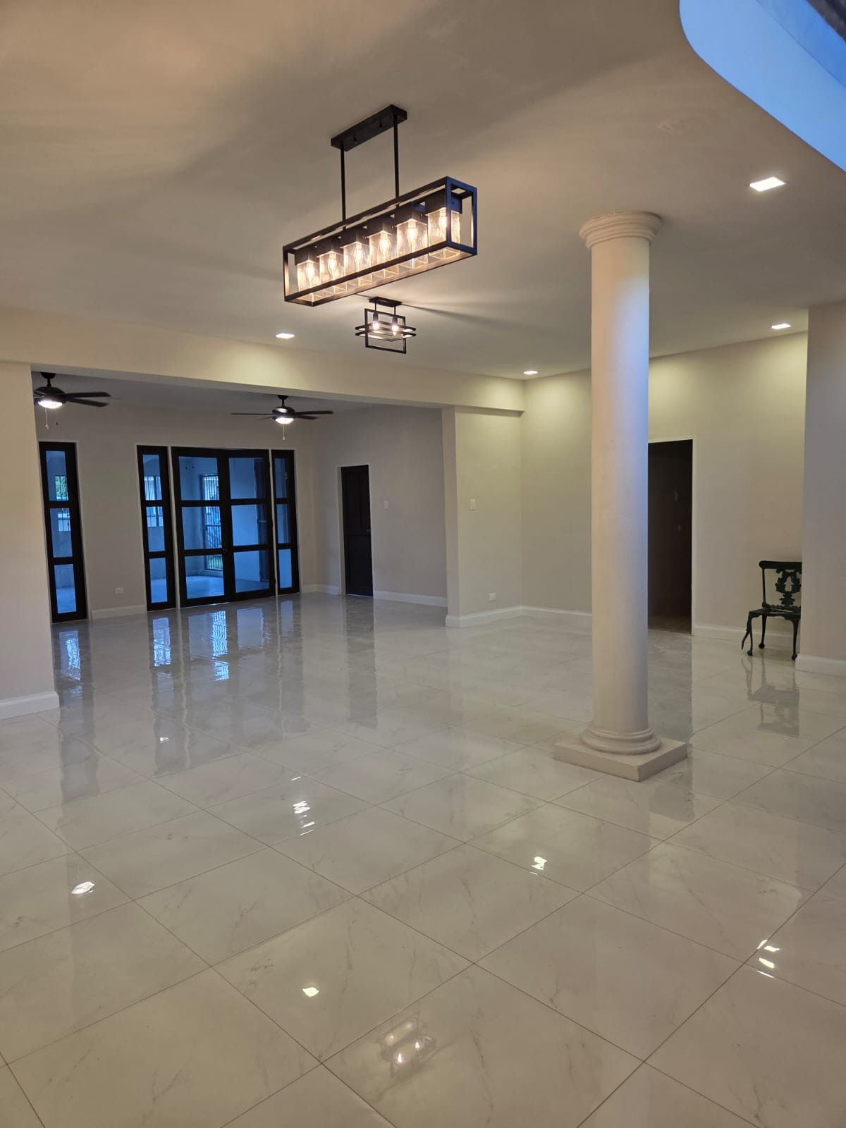 Open-concept living area with marble-look floor tiles and black chandelier