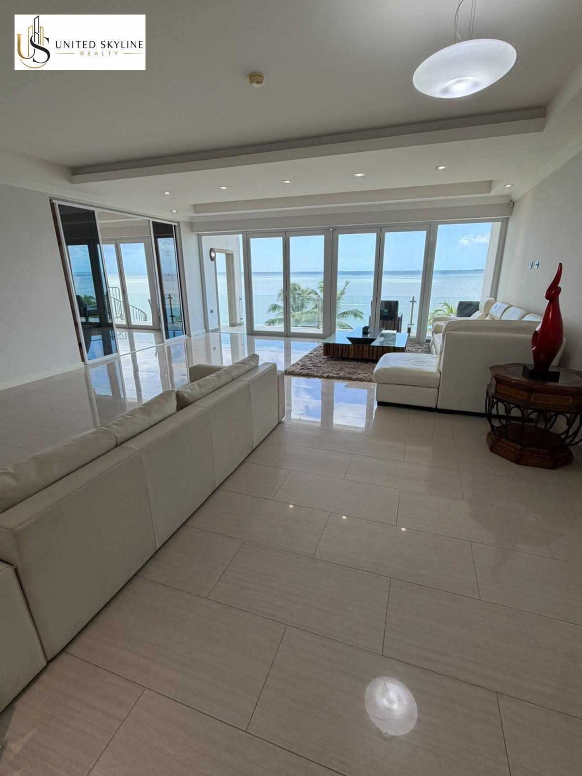 Spacious living room with white sofas and floor-to-ceiling doors overlooking the sea at Bel Air Bay